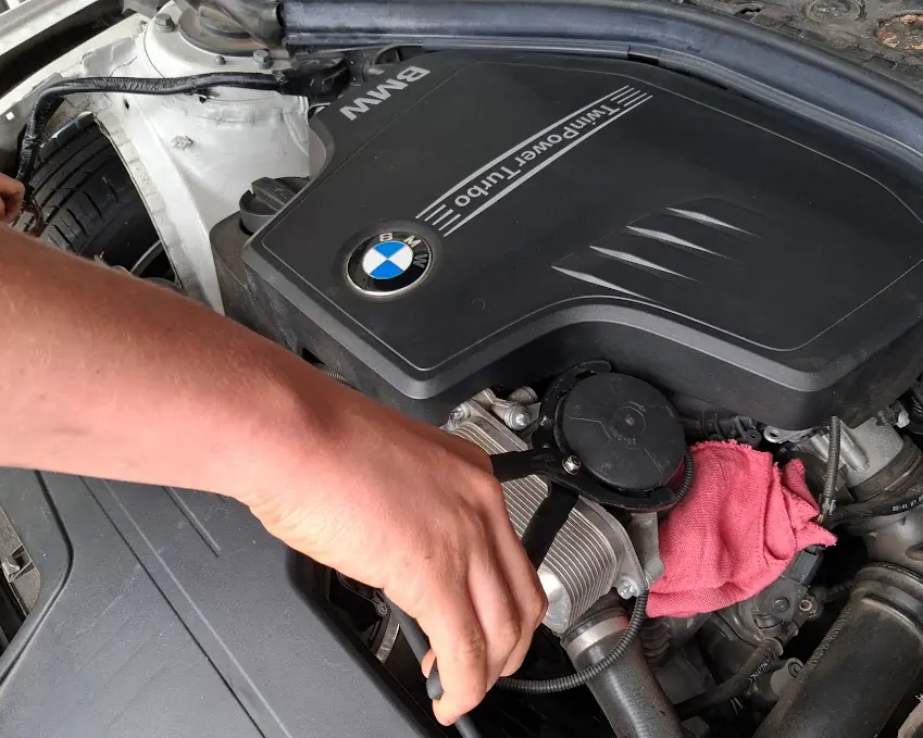 “Mobile mechanic performing under-hood maintenance on a car.