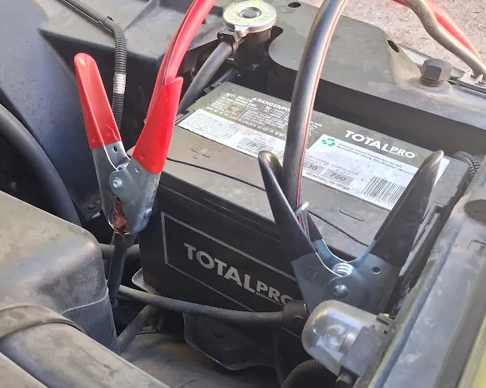 Roadside jump-start cables connected to a vehicle battery